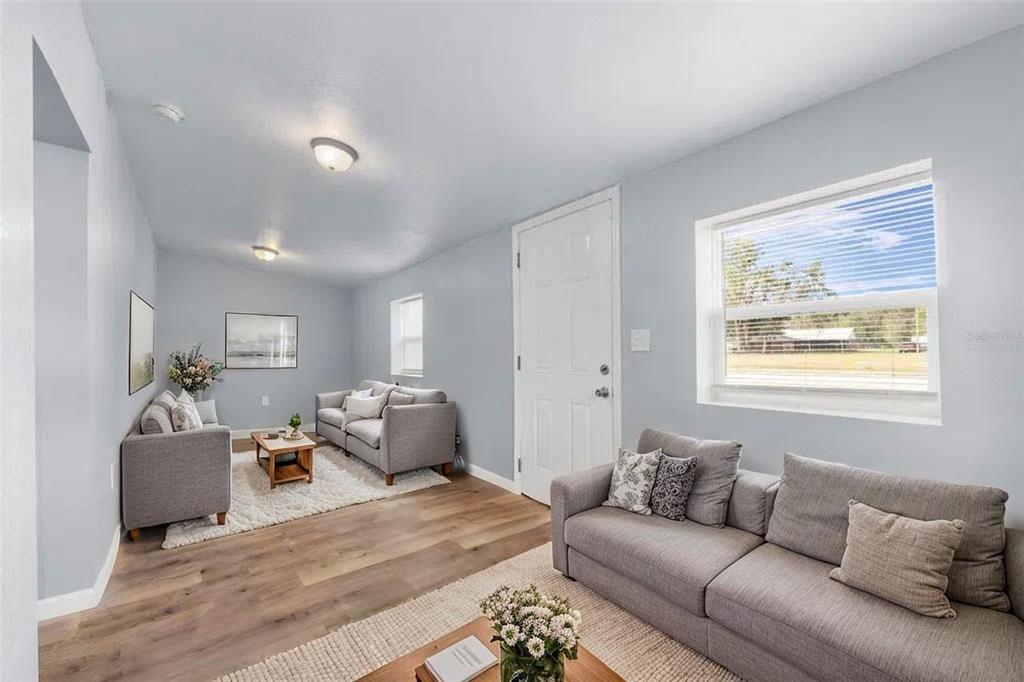A living room with light gray walls, wood-look flooring, two gray sofas, and two rugs — 515 S CHARLESTON AVENUE, FORT MEADE, FL