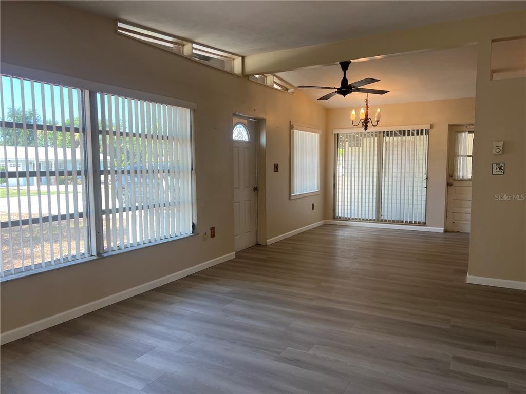 An interior view of a living area featuring light wood-look flooring and vertical window blinds — 321 ALBA STREET E, VENICE, FL