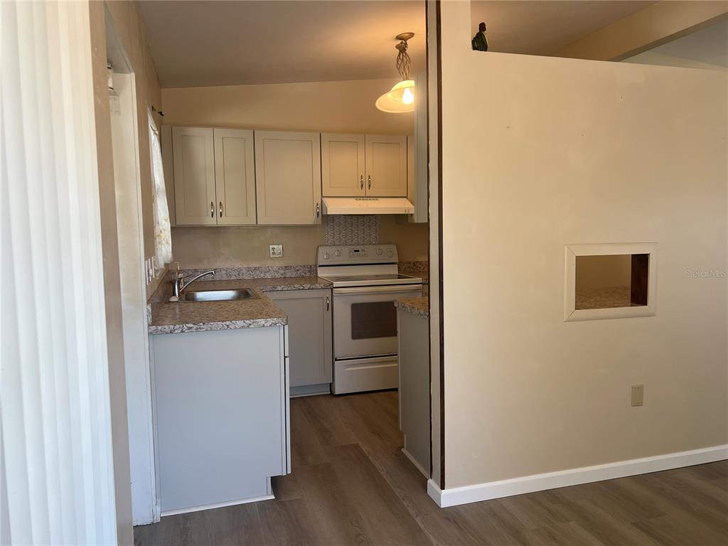 A small kitchen features light gray cabinets, a white stove, and speckled laminate countertops — 321 ALBA STREET E, VENICE, FL