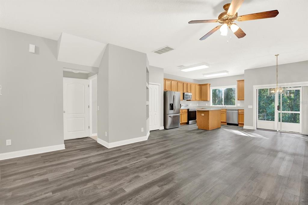 An open-concept kitchen and living area features light gray walls and wood-look laminate flooring — 17454 STINCHAR DRIVE, LAND O LAKES, FL