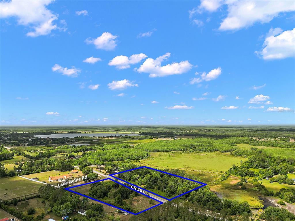 An aerial view shows a wooded plot of land outlined in blue near a road — 7845 COUNTY ROAD 561, CLERMONT, FL