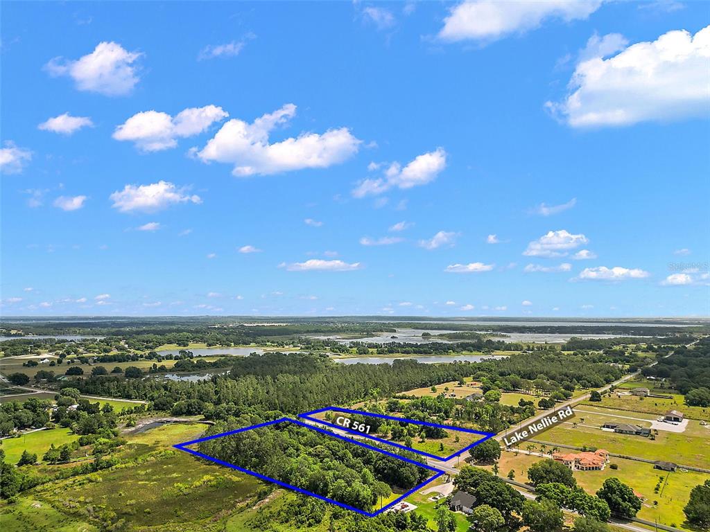An aerial view shows a wooded plot of land outlined in blue near a road — 7845 COUNTY ROAD 561, CLERMONT, FL