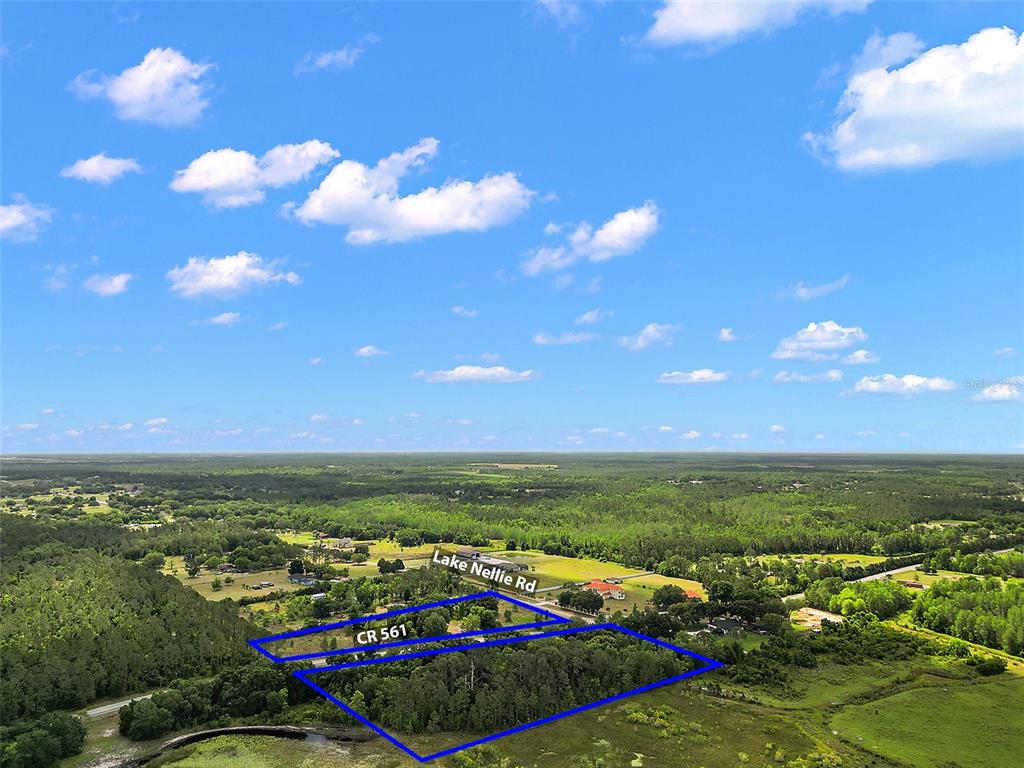 An aerial view shows a wooded plot of land outlined in blue near a road — 7845 COUNTY ROAD 561, CLERMONT, FL