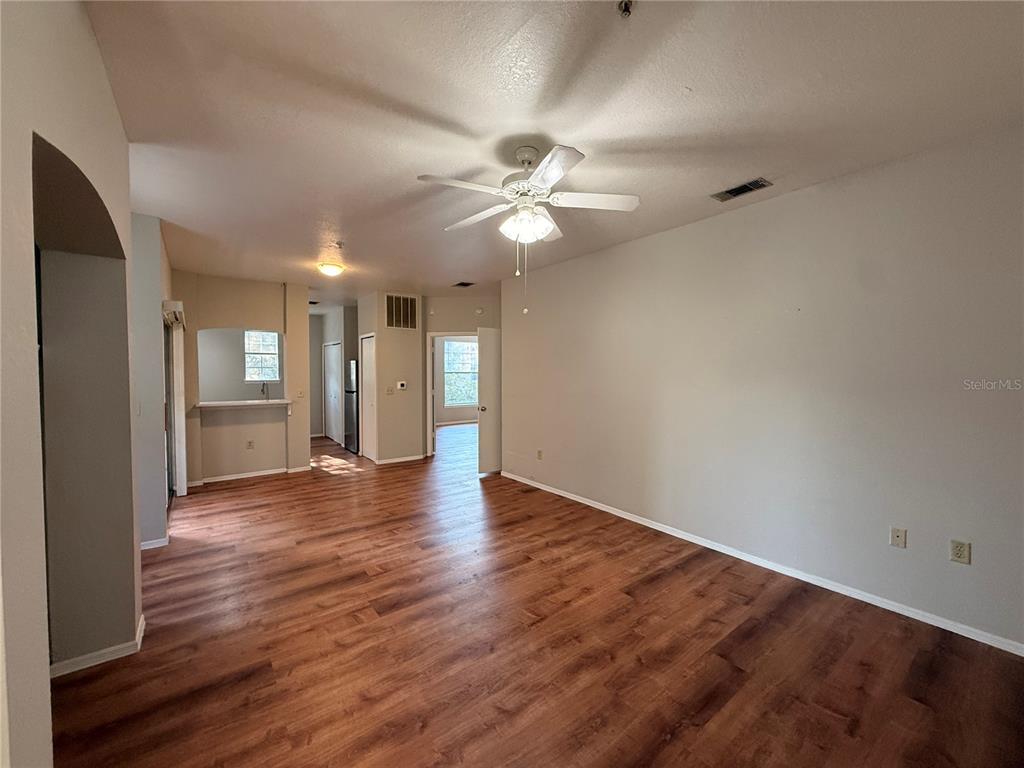 A living room with wood-look flooring, a ceiling fan, and an open kitchen pass-through — 102 VISTA VERDI CIRCLE UNIT 212, LAKE MARY, FL