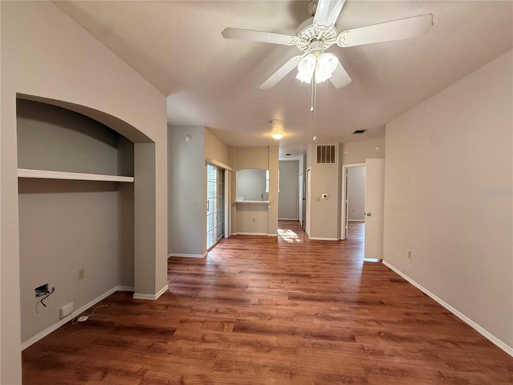 An open-concept living area features wood-look flooring, a ceiling fan, and a recessed wall niche — 102 VISTA VERDI CIRCLE UNIT 212, LAKE MARY, FL