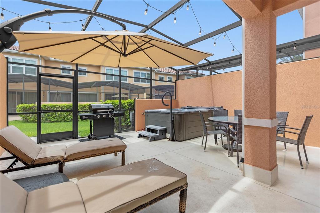 A screened-in patio features a hot tub, dining set, lounge chairs, and a grill — 2634 CORVETTE LANE, KISSIMMEE, FL