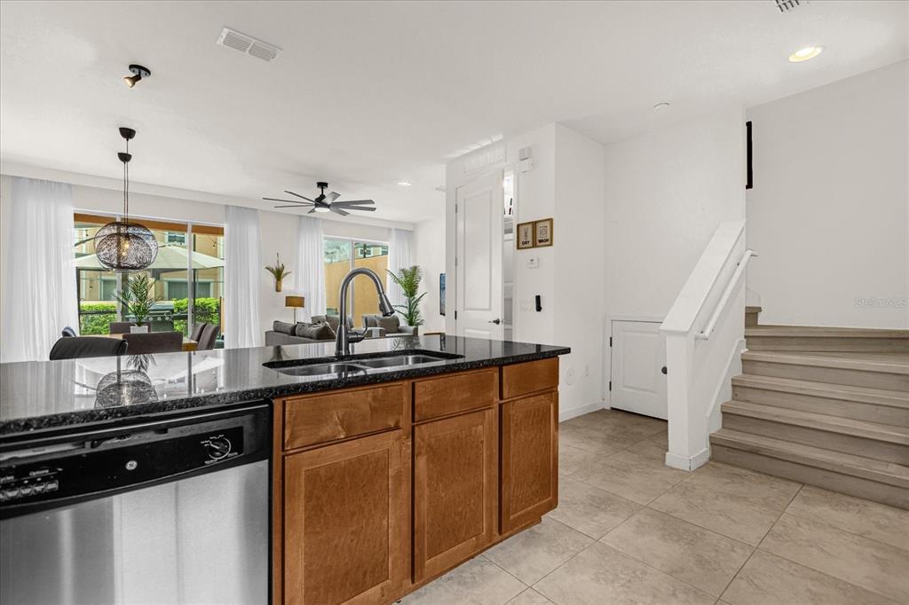 A kitchen island with a stainless steel dishwasher faces a living area and staircase — 2634 CORVETTE LANE, KISSIMMEE, FL
