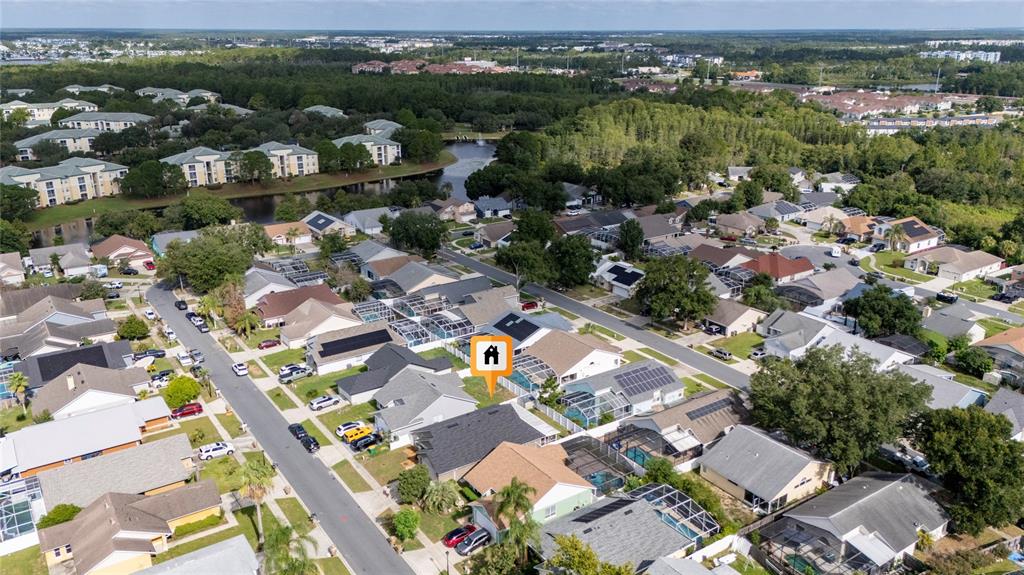 An aerial view shows a suburban neighborhood with single-family homes, swimming pools, and green spaces — 8809 PARLIAMENT COURT, KISSIMMEE, FL