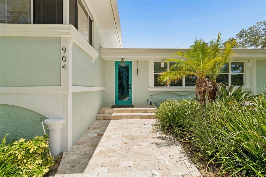 A light green house exterior features a teal front door and a stone walkway — 904 BAYSHORE DRIVE, TARPON SPRINGS, FL