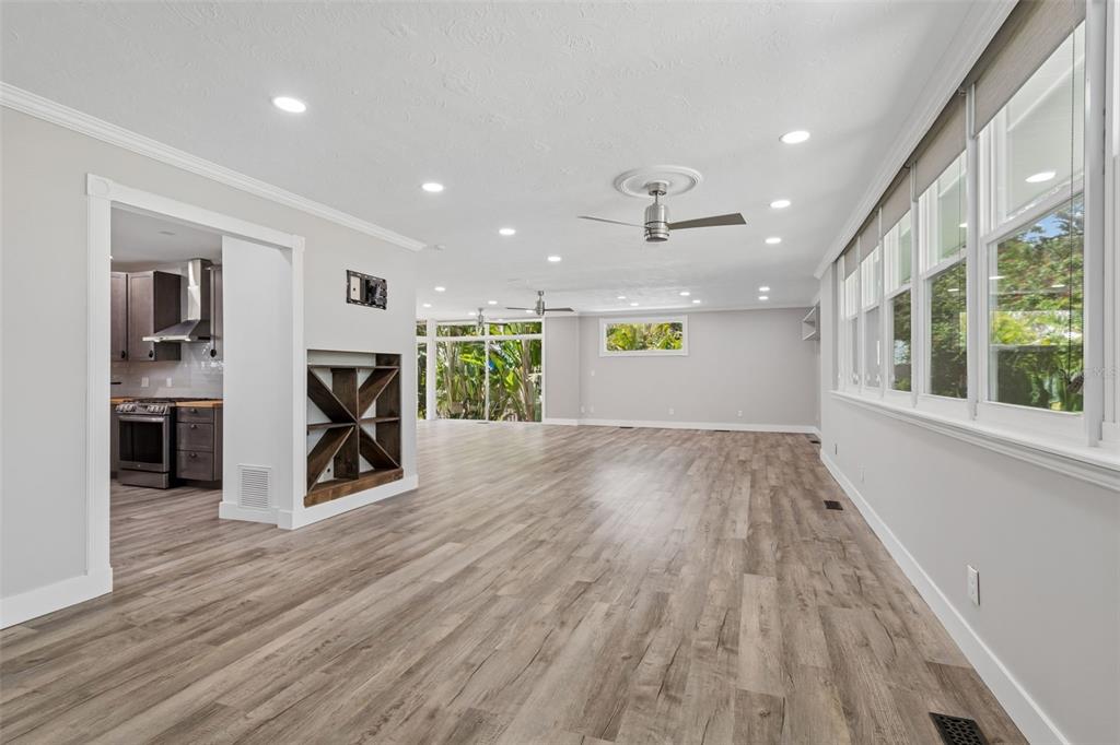 A spacious living area with light wood-look flooring, recessed lighting, and a view into the kitchen — 904 BAYSHORE DRIVE, TARPON SPRINGS, FL