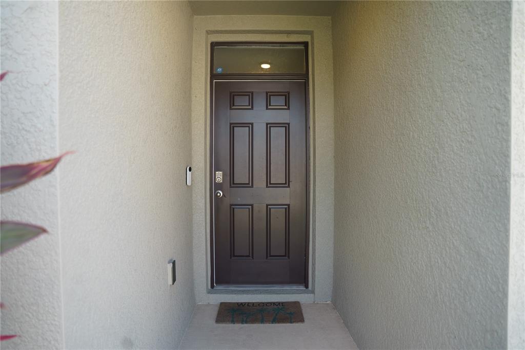 A dark brown front door with a transom window is set in a recessed entryway — 2614 GREENLEAF TERRACE, PARRISH, FL