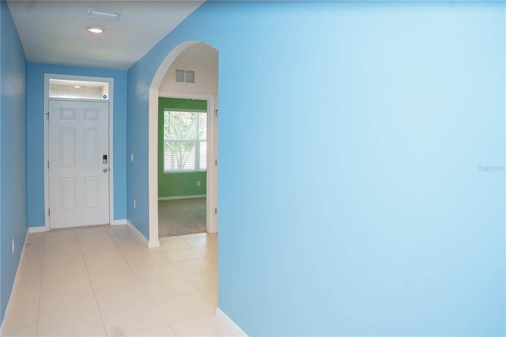An entryway with light blue walls, tile flooring, and an arched doorway leading to another room — 2614 GREENLEAF TERRACE, PARRISH, FL