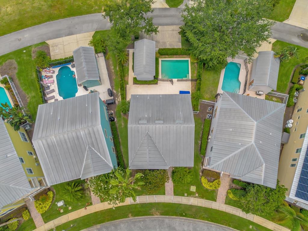 An aerial view shows three houses with metal roofs, private pools, and small detached structures — 7766 LINKSIDE LOOP, REUNION, FL
