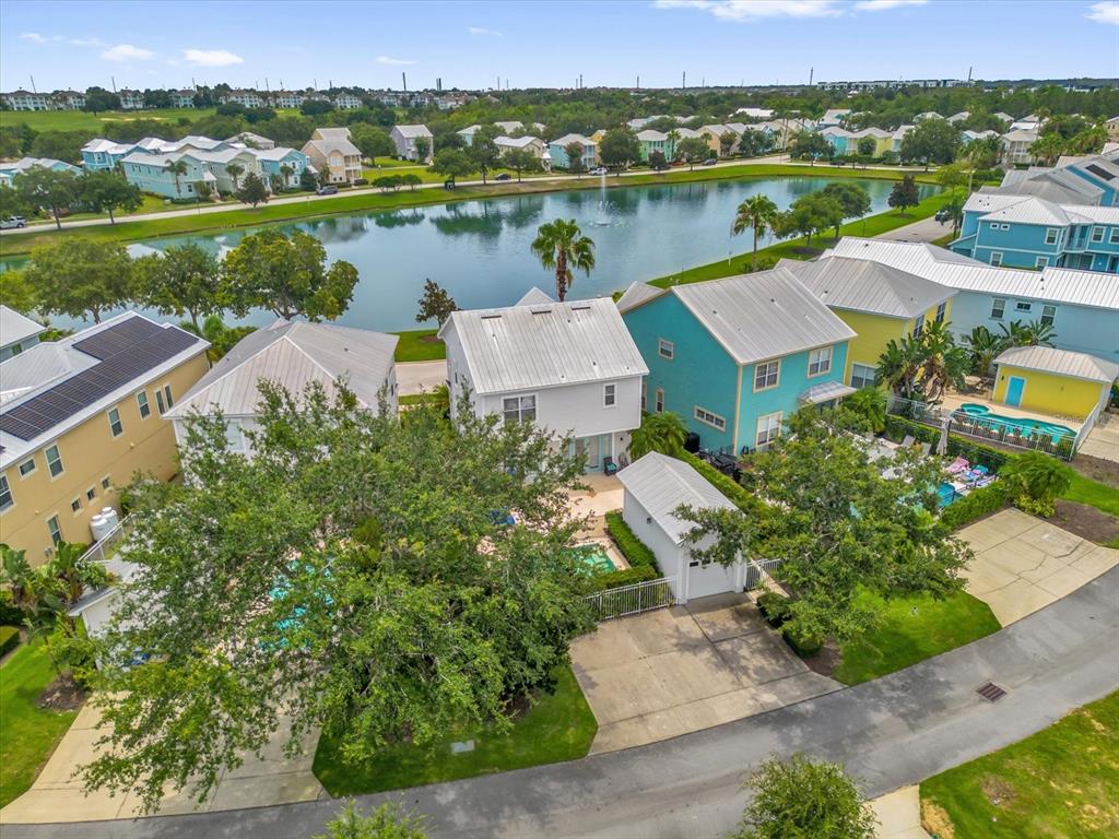 An aerial view shows several colorful houses with pools and a small lake nearby — 7766 LINKSIDE LOOP, REUNION, FL