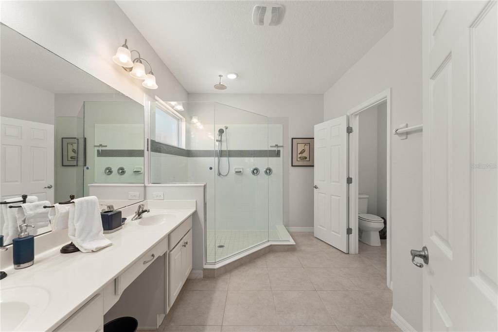 A bathroom features a double vanity, a glass-enclosed walk-in shower, and a separate toilet room — 4429 SHIVA LOOP, KISSIMMEE, FL