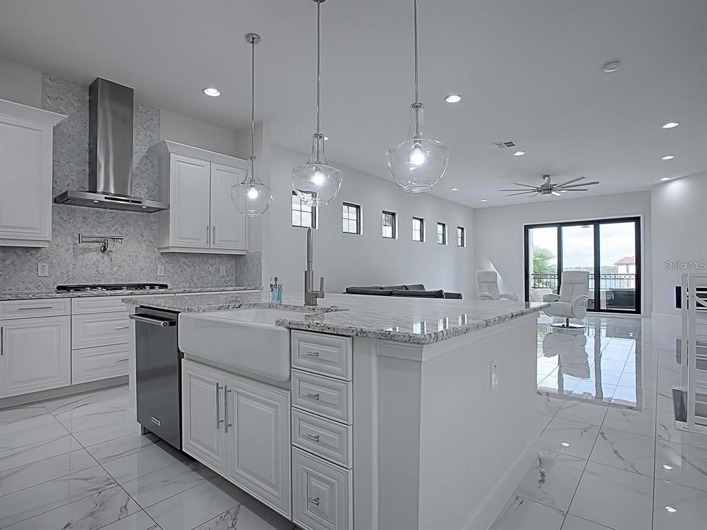 A modern white kitchen features a farmhouse sink, marble-patterned floors, and three glass pendant lights — 7661 TOSCANA BOULEVARD, ORLANDO, FL
