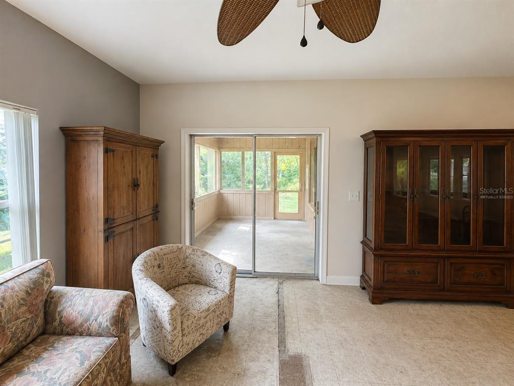 A living room features two large wooden cabinets, a patterned armchair, and a sliding glass door — 6013 IDLE A WHILE CIRCLE, DADE CITY, FL