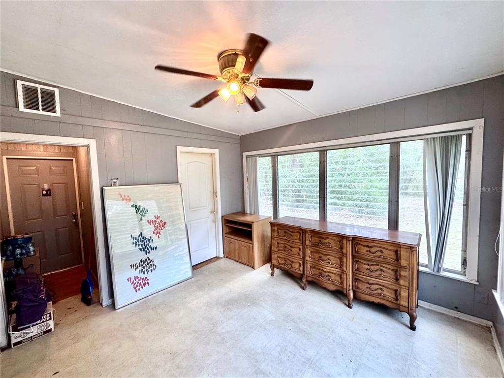 A room with gray paneled walls, a ceiling fan, a large dresser, and windows — 6013 IDLE A WHILE CIRCLE, DADE CITY, FL