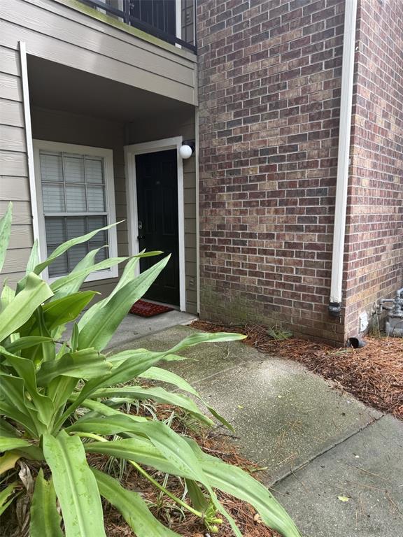 A two-story apartment building exterior features tan siding, brick accents, and an outdoor metal staircase — 5136 PARK CENTRAL DRIVE UNIT 215, ORLANDO, FL