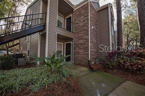A bedroom with light-colored walls, wood-look flooring, a ceiling fan, and two white doors — 5136 PARK CENTRAL DRIVE UNIT 215, ORLANDO, FL