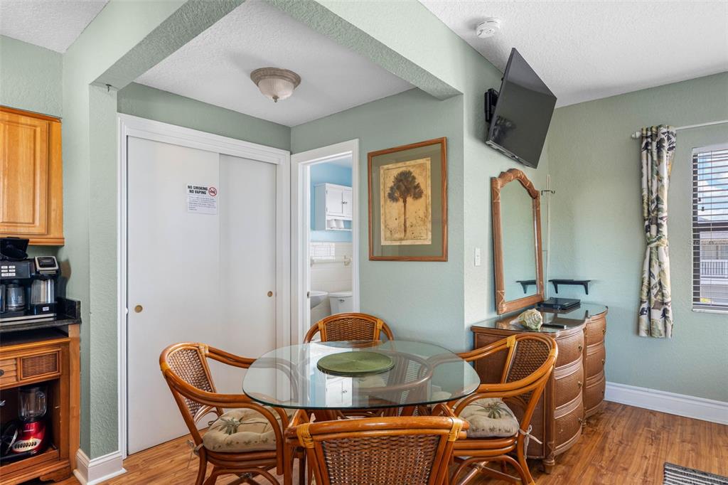 A dining area features a glass-topped wicker table, four chairs, a dresser, and a television — 16333 GULF BOULEVARD UNIT 210, REDINGTON BEACH, FL