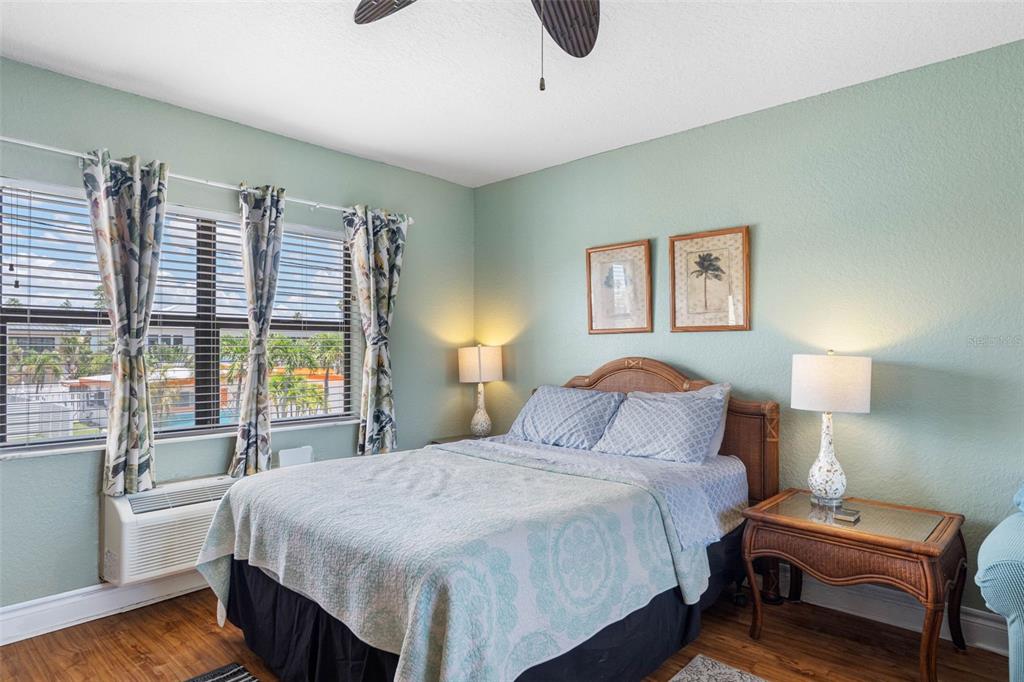 A bedroom with a bed, two nightstands, and a window overlooking a parking lot — 16333 GULF BOULEVARD UNIT 210, REDINGTON BEACH, FL