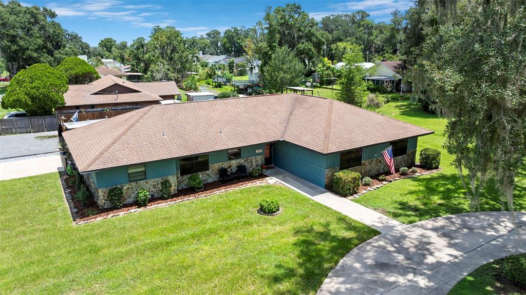 An aerial view shows a single-story house with a brown roof, stone siding, and blue trim — 1351 CR 482N, LAKE PANASOFFKEE, FL