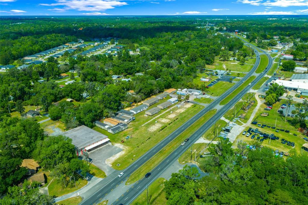 An aerial view shows a multi-lane highway running through a wooded area with commercial buildings — 4450 S PINE AVENUE, OCALA, FL