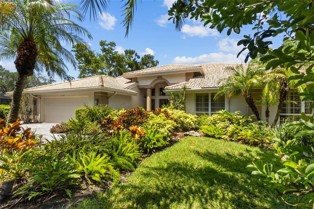A single-story house with a tiled roof, a two-car garage, and lush tropical landscaping — 5166 KESTRAL PARK TERRACE, SARASOTA, FL