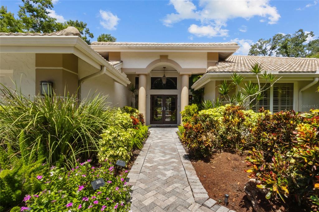 A paved walkway leads to the front entrance of a house with a tiled roof — 5166 KESTRAL PARK TERRACE, SARASOTA, FL