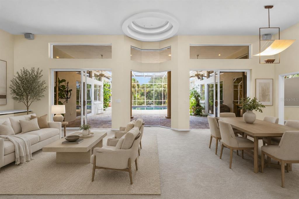 A bright living and dining area features neutral furniture, high ceilings, and sliding doors to a pool — 5166 KESTRAL PARK TERRACE, SARASOTA, FL