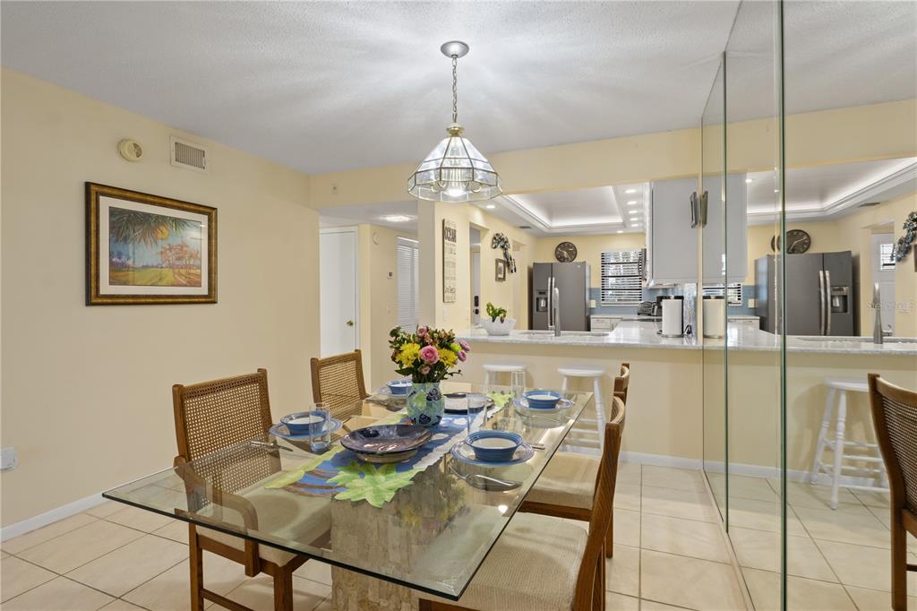 A dining area with a glass table and chairs sits adjacent to an open kitchen — 5608 GULF DRIVE UNIT 104, HOLMES BEACH, FL