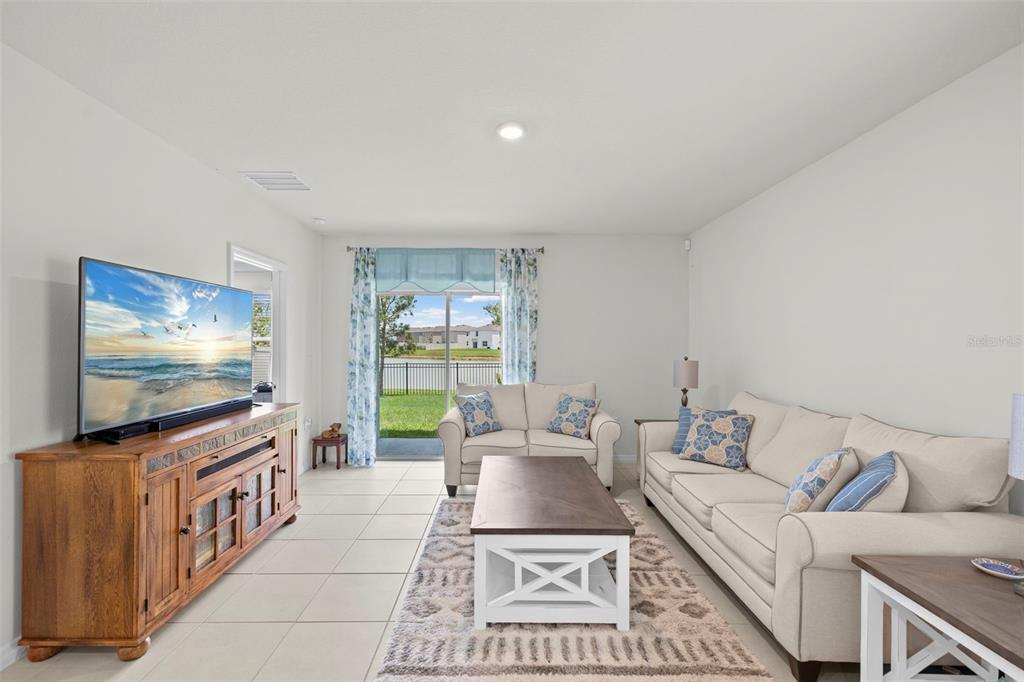 A living room features a large television on a wooden console, sofa, and sliding glass doors — 10914 PENNY GALE LOOP, SAN ANTONIO, FL