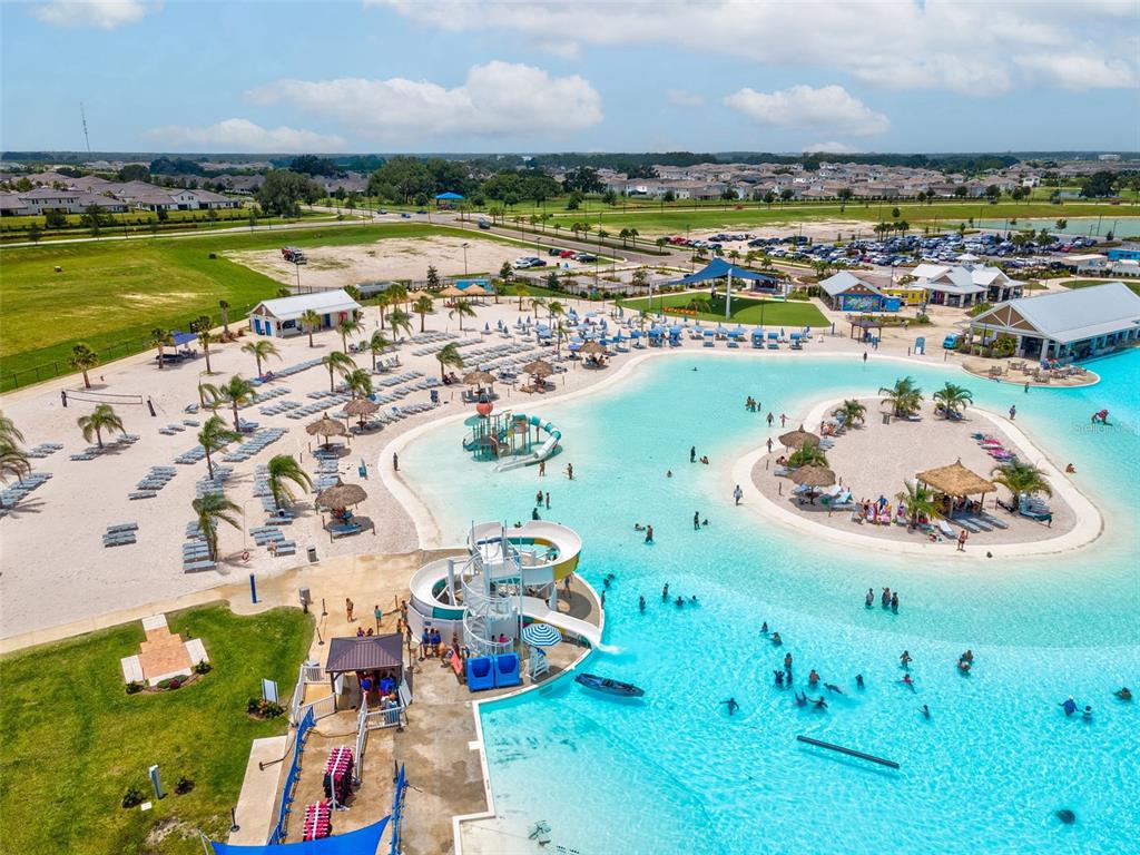 An aerial view of a large turquoise swimming lagoon with a waterslide and sandy beach — 10914 PENNY GALE LOOP, SAN ANTONIO, FL