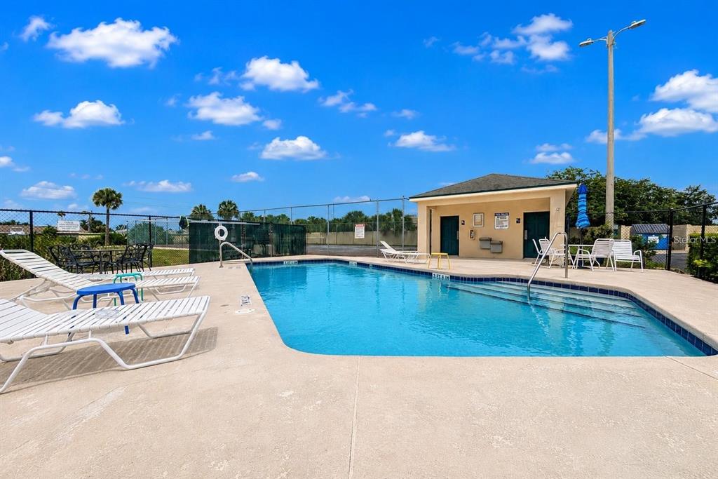 An outdoor swimming pool with lounge chairs and a small clubhouse under a blue sky — 644 YARDARM DRIVE UNIT 22, APOLLO BEACH, FL