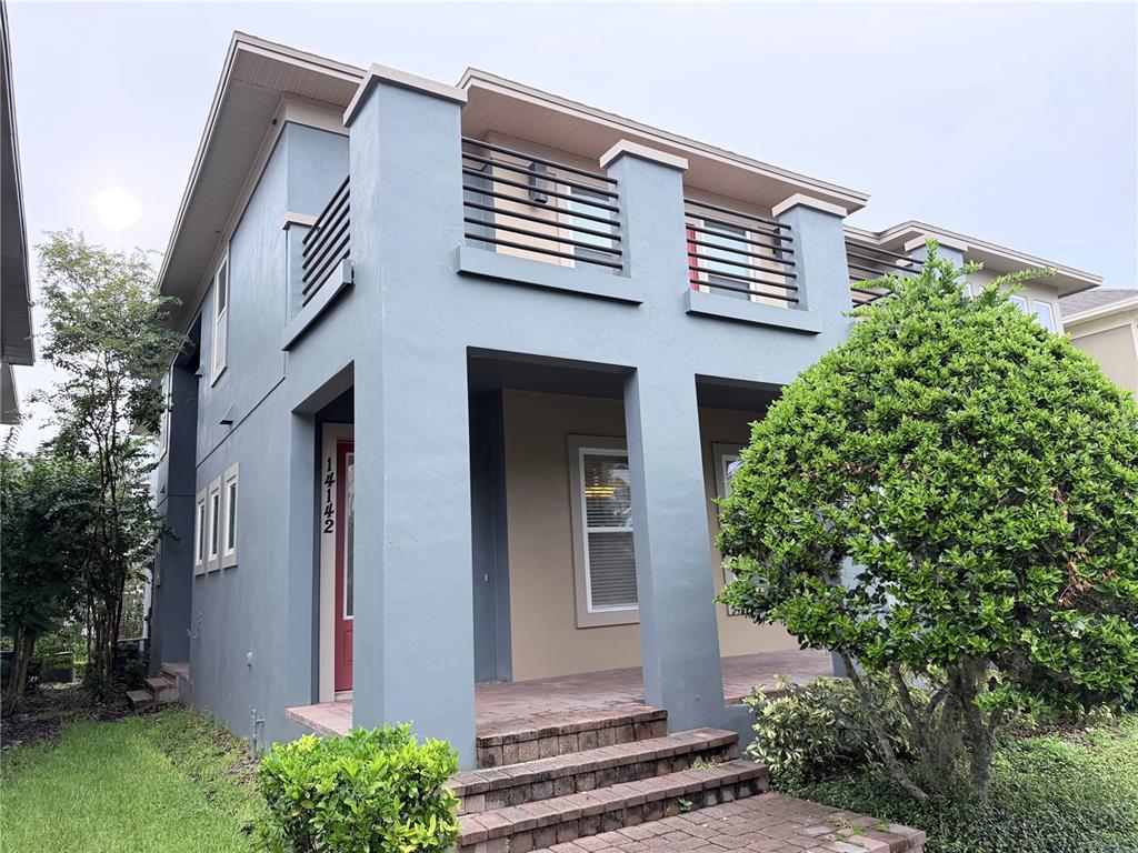A two-story blue house features a front porch, brick steps, and a second-floor balcony — 14142 WALCOTT AVENUE, ORLANDO, FL