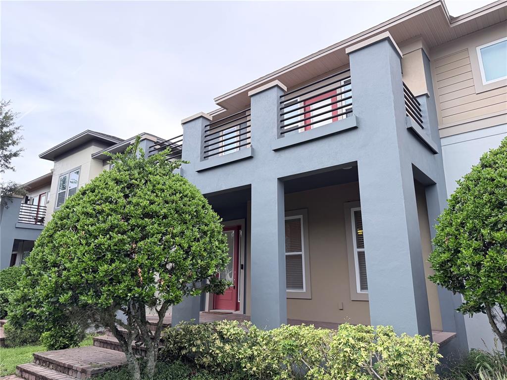 A two-story house exterior features a blue stucco facade, a balcony, and a red door — 14142 WALCOTT AVENUE, ORLANDO, FL