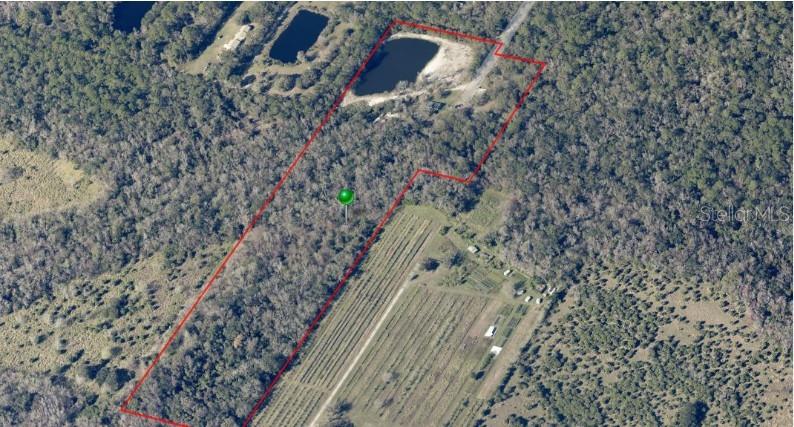 An aerial view shows a wooded plot of land outlined in red near a pond — 270 WRIGHT GROVE ROAD, OAK HILL, FL