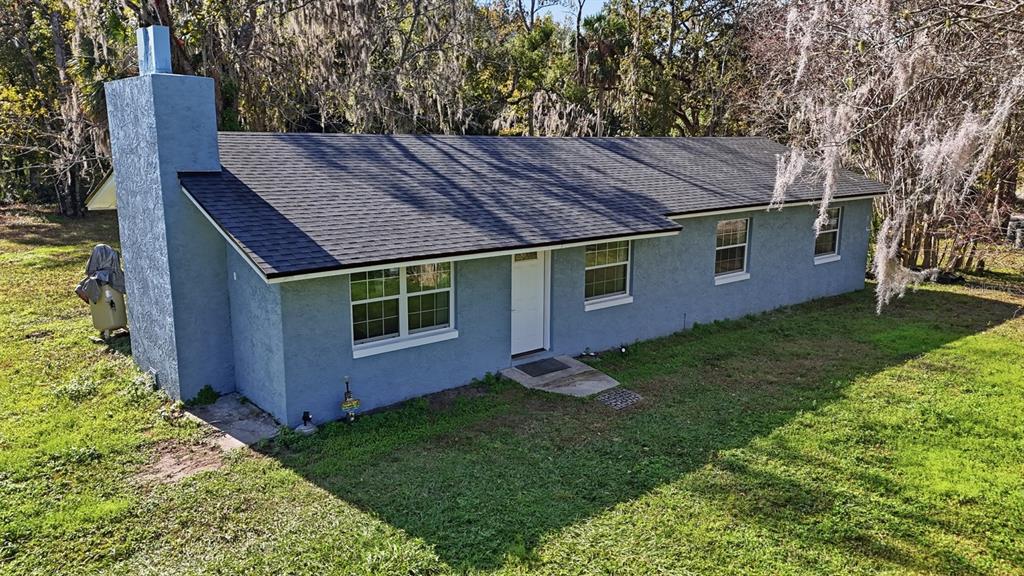A blue, single-story house with a dark shingled roof and a prominent exterior chimney — 270 WRIGHT GROVE ROAD, OAK HILL, FL