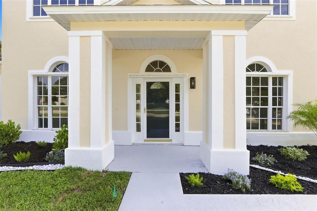 The exterior of a house features a covered entryway with white pillars and a front door — 2520 MILLRACE WAY, MERRITT ISLAND, FL