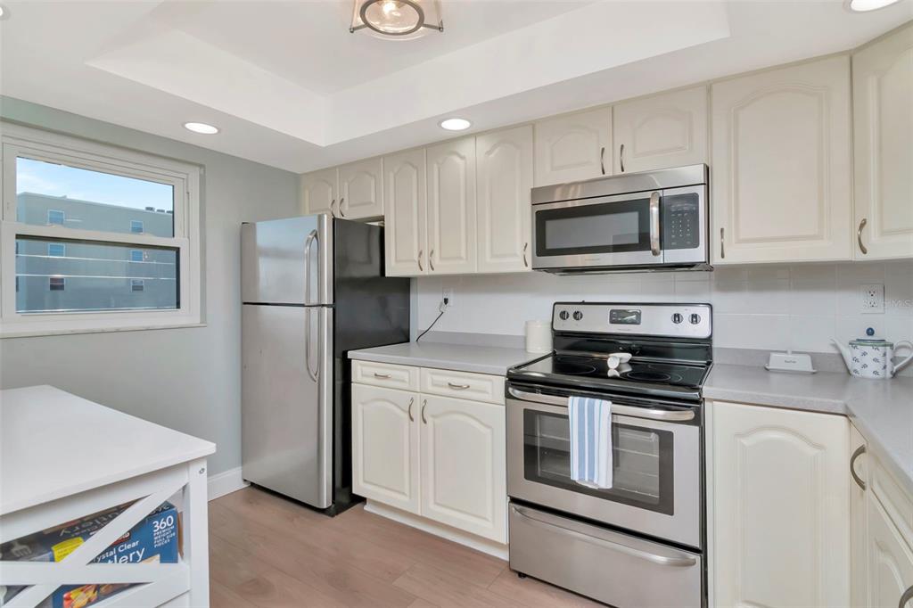 A kitchen features white cabinets, stainless steel appliances, and a pass-through window to the dining area — 17580 GULF BOULEVARD UNIT 403, REDINGTON SHORES, FL