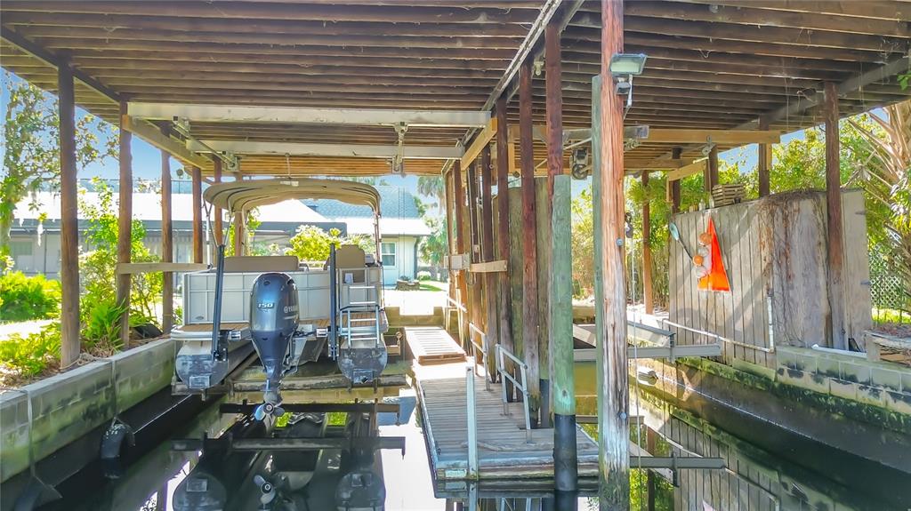 A covered boat slip with a pontoon boat docked on a lift over the water — 536 NW 9TH AVENUE, CRYSTAL RIVER, FL