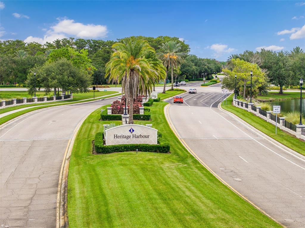An aerial view shows the entrance to the Heritage Harbour community with landscaped medians — 8815 BROOKFIELD TERRACE, BRADENTON, FL