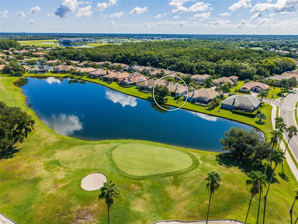 An aerial view shows a house circled on a lakefront lot next to a golf course — 8815 BROOKFIELD TERRACE, BRADENTON, FL