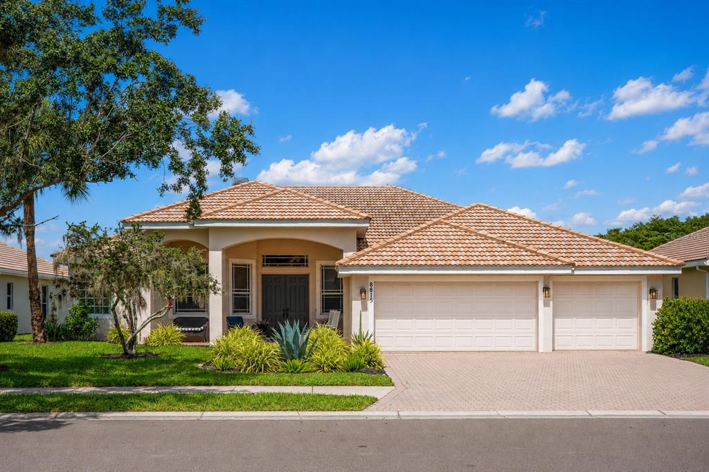 A single-story house with a beige stucco exterior, a tiled roof, and a three-car garage — 8815 BROOKFIELD TERRACE, BRADENTON, FL