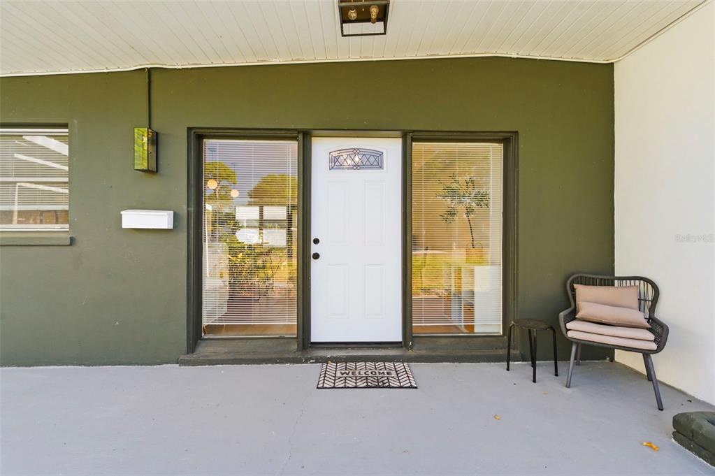 A white front door is flanked by two large windows on a covered porch — 6350 HAMPTON DRIVE N, ST PETERSBURG, FL