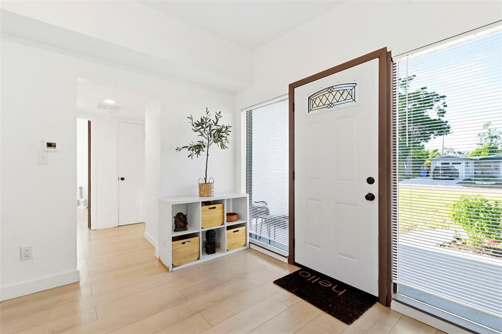 A bright entryway features light wood flooring, a white storage unit, and a front door — 6350 HAMPTON DRIVE N, ST PETERSBURG, FL
