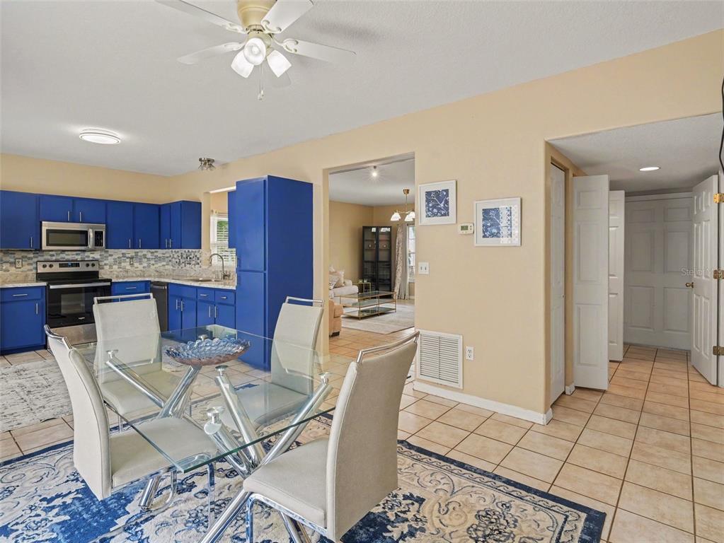 A dining area with a glass table and blue cabinets in the adjacent kitchen — 3715 E 31ST STREET, BRADENTON, FL