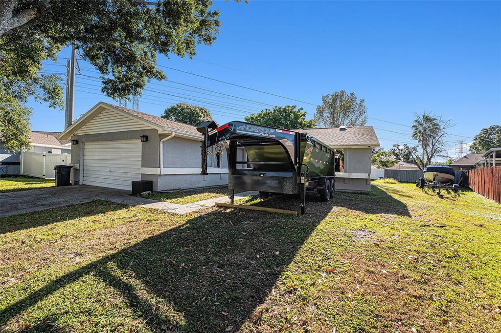 A single-story house with a garage and a large dump trailer parked in the yard — 645 TIMBER BAY CIRCLE E, OLDSMAR, FL