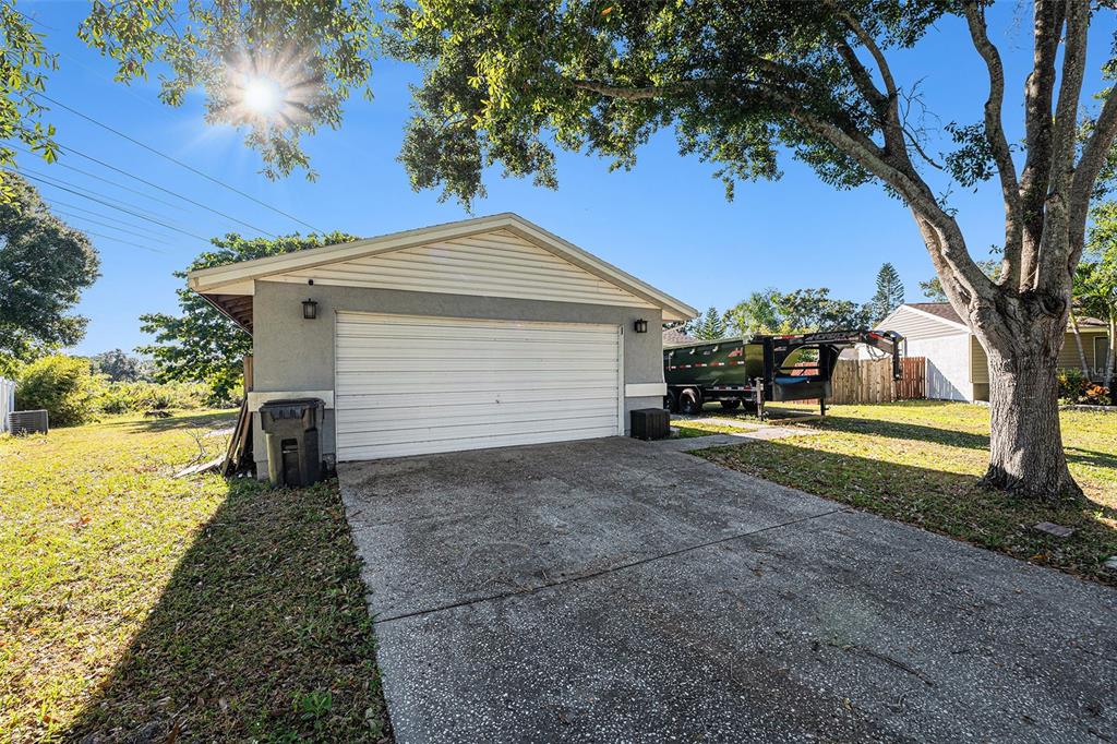 A detached garage with a white door, concrete driveway, and a trailer parked beside it — 645 TIMBER BAY CIRCLE E, OLDSMAR, FL